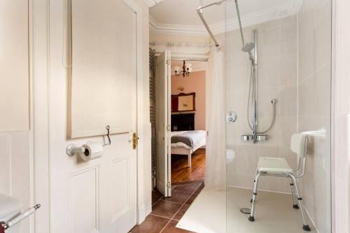 La salle de bains est pourvue d'une douche et d'une porte avec une chaise. dans l'établissement Lochinver, à Crieff