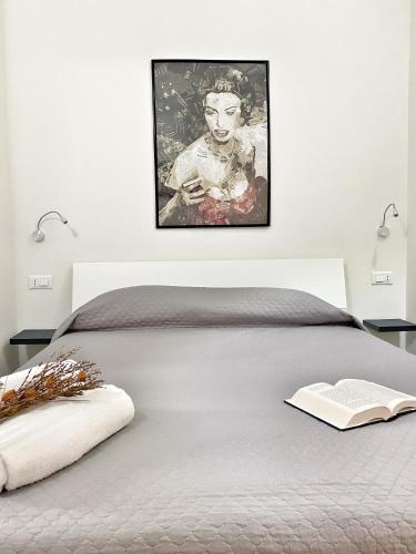 a bedroom with a bed with a picture on the wall at DOMOBLU Camere In Centro in Tortolì