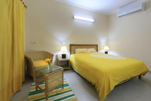 a bedroom with a yellow bed and a chair at Cox's Bazar Surf Club Resort & Cafe in Cox's Bazar