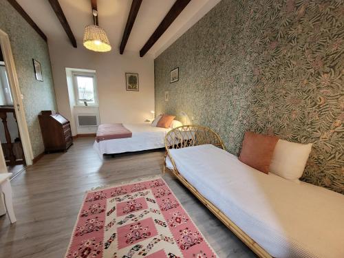 a room with two beds and a couch and a rug at le Milin Du in Gouarec