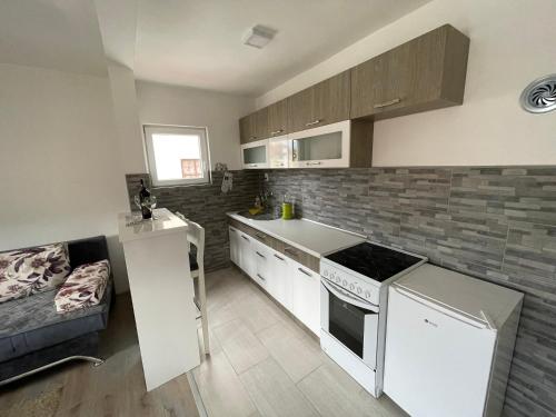 - une cuisine avec des appareils blancs et un canapé dans la chambre dans l'établissement Apartman Mila, à Višegrad