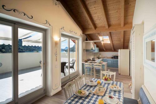 a room with a table and chairs and a kitchen at Attico con vista sul lago e montagne a Molveno in Molveno