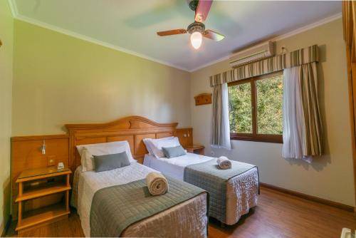 a bedroom with two beds and a window at Pousada Monte Felice Recanto da Lua in Gramado