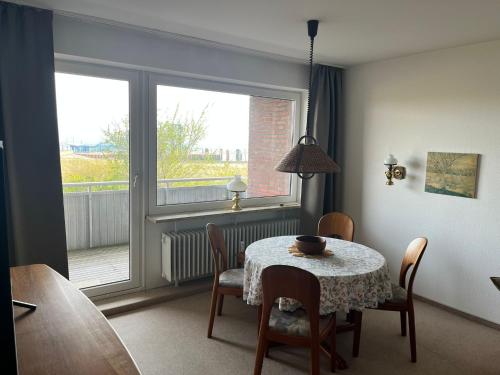 ein Esszimmer mit einem Tisch, Stühlen und einem Fenster in der Unterkunft Haus Seelöwe Wohnung 1 in Wittdün