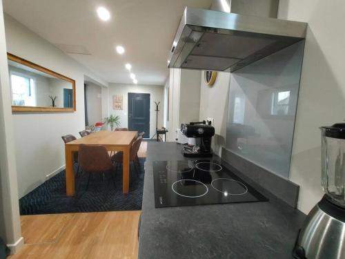 Il comprend une cuisine équipée d'une cuisinière. four supérieur à côté d'une table dans l'établissement Maison et parking privé proche zénith et volcans., à Le Cendre