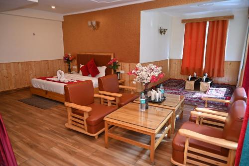 Hotel Seven Hills Manali في مانالي: غرفة فندقية بسرير وطاولة وكراسي