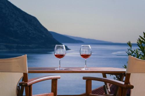 two glasses of wine sitting on a table near the water at Pavio in Póros Kefalonias