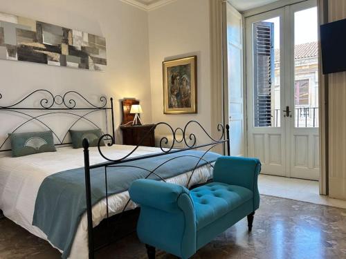 a bedroom with a bed and a blue chair at Appartamento “Al Duomo” Catania in Catania