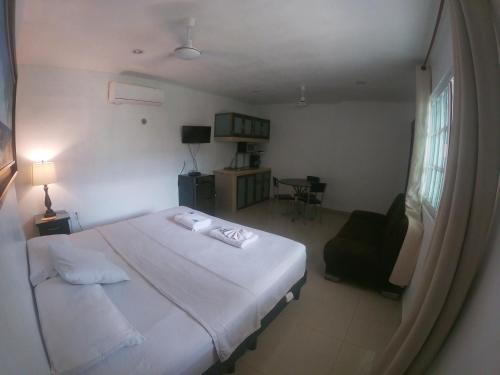 - une chambre avec un grand lit blanc et une chaise dans l'établissement Villas Karalv, à Bacalar