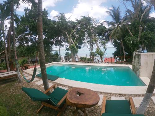 a swimming pool with chairs and a table and the ocean at Villas Karalv in Bacalar