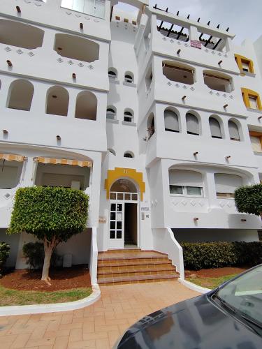 a white building with a door and a tree at Bungalows del Golf Almerimar in Almerimar