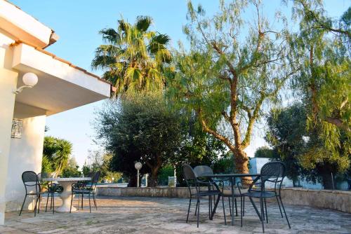 a patio with a table and chairs and trees at La Maison One B&B in Carovigno