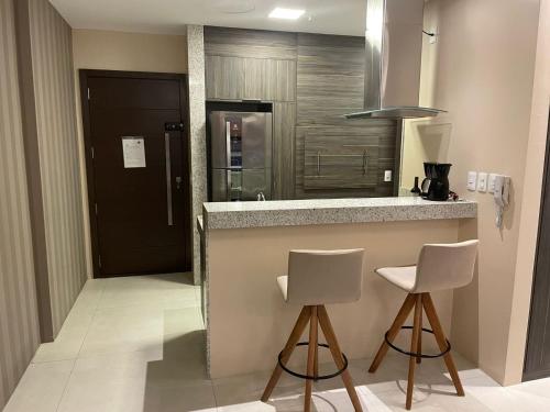 a kitchen with two bar stools and a counter top at Loft com vista incrível no Barra Shopping in Porto Alegre