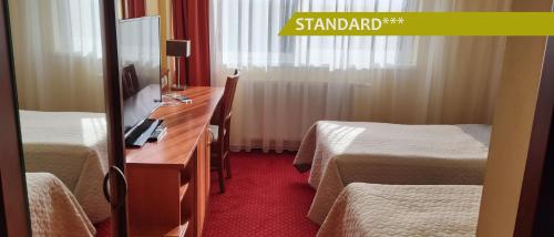 a hotel room with two beds and a desk with a mirror at Hotel Ludmila in Mělník