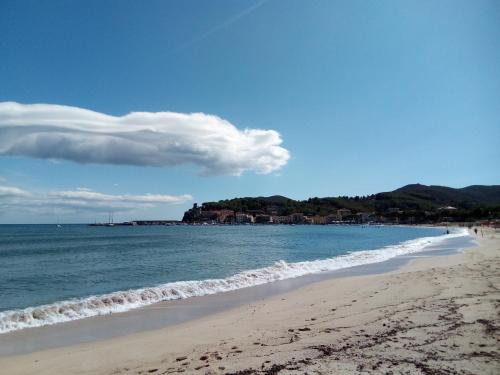 a beach with people walking on the sand and the water at Hotel Meridiana in Marina di Campo
