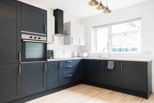 a kitchen with blue cabinets and a sink and a window at Charming 3 bedroom Belfast townhouse in Belfast