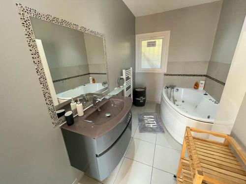 Un baño con lavabo, bañera y espejo. en belle villa, piscine, jacuzzi, en Six-Fours-les-Plages