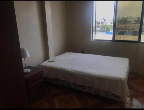 a small bedroom with a bed and a window at Departamentos de la Costa in Machala
