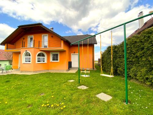 an orange house with a swing in a yard at Rekreační chalupa Ivon in Hŭry
