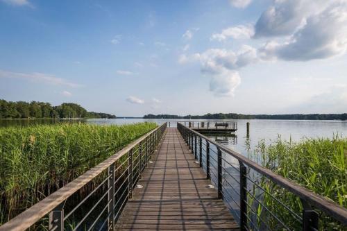 a wooden boardwalk over a lake with a dock at Ferienwohnung Seestern in Bad Saarow