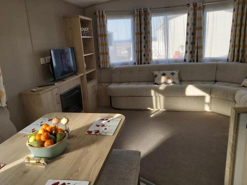 a living room with a bowl of fruit on a table at Caravan By The Sea in Elgin