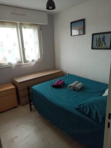 une chambre avec un lit bleu avec deux serviettes dessus dans l'établissement Cabourg: Petit F2 proche hippodrome., à Cabourg