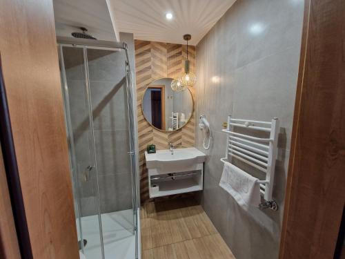 a bathroom with a shower and a sink and a mirror at Hotel Verde Montana Wellness & Spa in Kudowa-Zdrój