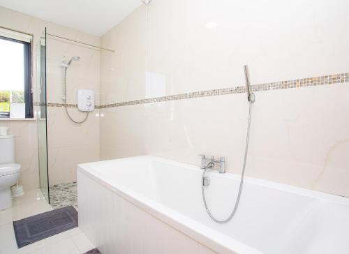 La salle de bains blanche est pourvue d'une baignoire et d'une douche. dans l'établissement Lakeview Waterville Holiday Home, à Waterville