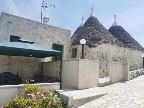 a stone building with a green umbrella in front of it at Trullo Le Tre Sorelle in Cisternino