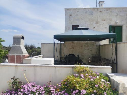 a patio with a blue umbrella and some flowers at Trullo Le Tre Sorelle in Cisternino