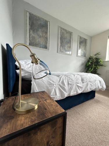 ein Schlafzimmer mit einem Bett und einem Schreibtisch mit einer Lampe in der Unterkunft 4 Bedroom House EMA with Parking and Garage in Castle Donington