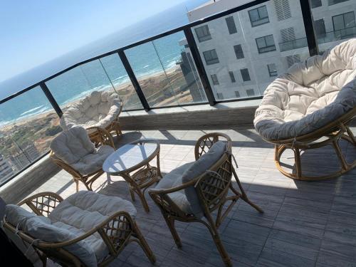 een groep stoelen en tafels op een balkon met uitzicht op de oceaan bij panoramic apartment EdenTower in Bat Yam