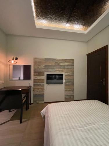 a bedroom with a bed and a desk and a television at Grand Lodge Langkawi in Pantai Cenang