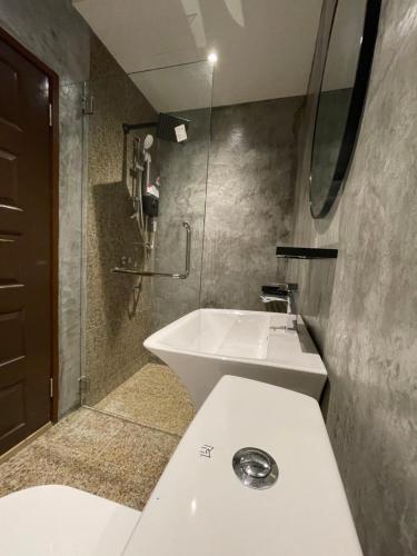 uma casa de banho com um lavatório branco e um chuveiro em Grand Lodge Langkawi em Pantai Cenang