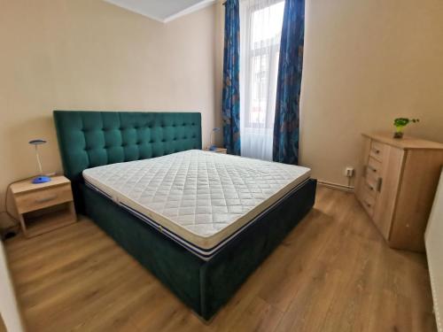 a bedroom with a bed with a green headboard and a window at Petőfi Apartment in Miercurea-Ciuc