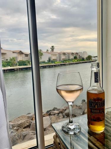 - un verre de vin blanc à côté d'une bouteille de bière dans l'établissement Appartement Vue Mer - RDC - Parking Privé - Meublé Tourisme 4 étoiles, au Cap d'Agde