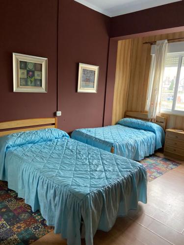 2 Betten in einem Schlafzimmer mit blauer Bettwäsche in der Unterkunft Hospedaje FranXu in Fene