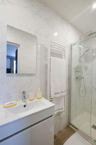 une salle de bain blanche avec un lavabo et une douche dans l'établissement Villa Forestière Studio Le Sophora, à Quincy-Voisins