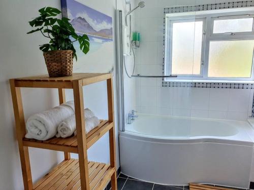 a bathroom with a tub and a plant on a shelf at Amber House Leisure & Contractors in Worting