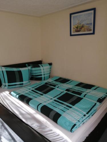 a bed with a blue and black blanket and pillows at Ferienwohnung auf Rügen in Putbus