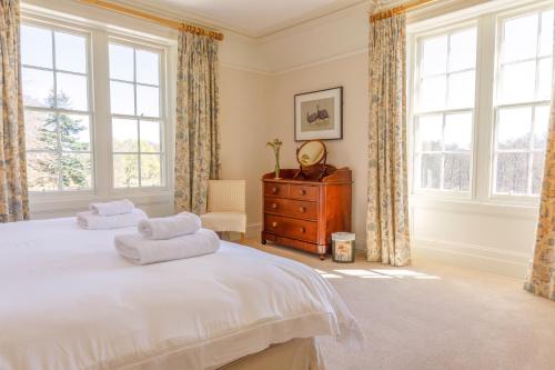 a bedroom with a bed and a dresser and windows at Dalgheal in Evanton