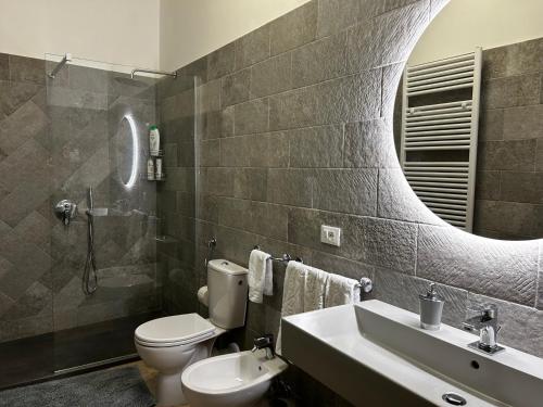 bagno con servizi igienici, lavandino e specchio di Sartinicco Apartment a Montepulciano