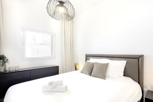 sypialnia z dużym białym łóżkiem z żyrandolem w obiekcie Luxury Tel Aviv Seaside by Airsuite w Tel Awiwie