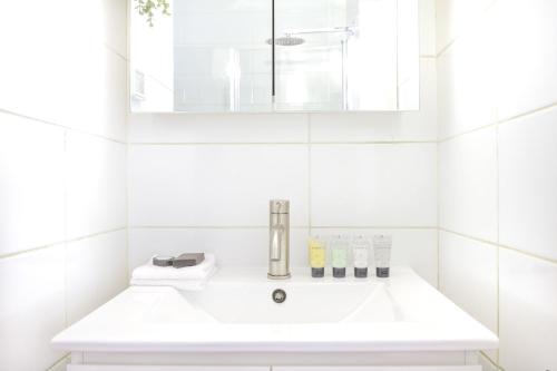W białej łazience znajduje się umywalka i lustro. w obiekcie Luxury Tel Aviv Seaside by Airsuite w Tel Awiwie