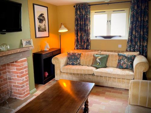 a living room with a couch and a fireplace at The Hayloft in Gestingthorpe