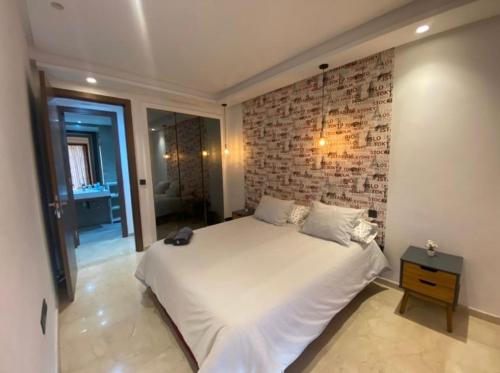 - une chambre avec un lit blanc et un mur en briques dans l'établissement Studio propre et calme Casablanca, à Casablanca