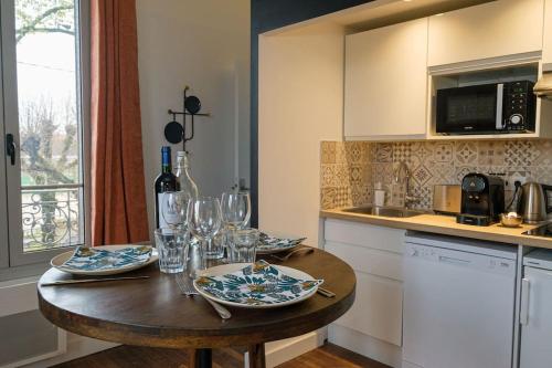 eine Küche mit einem Holztisch mit Tellern und Weingläsern in der Unterkunft Villa Forestière Studio L'Acacia in Quincy-Voisins