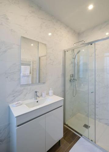 une salle de bain blanche avec un lavabo et une douche dans l'établissement Villa Forestière Studio L'Acacia, à Quincy-Voisins