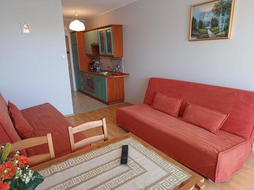 uma sala de estar com um sofá vermelho e uma cozinha em Studio Krynica em Krynica Morska