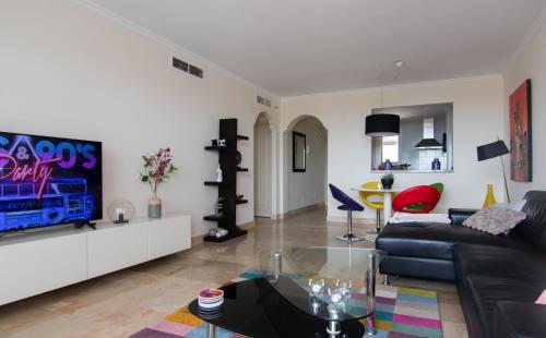 uma sala de estar com um sofá preto e uma televisão em Luxe appartement Las Palmeras Calahonda em Sitio de Calahonda